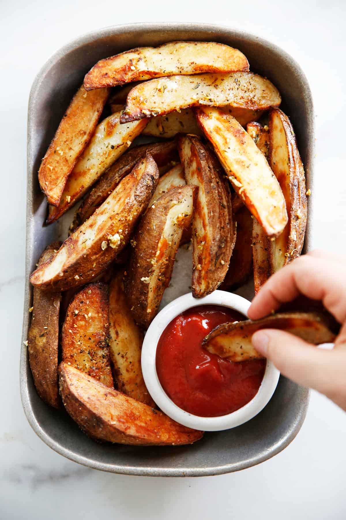 Roasted potato wedges on a serving platter with ketchup.