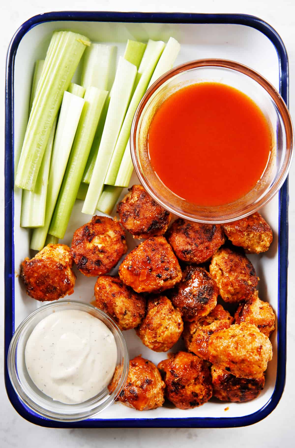 A platter of gluten-free buffalo chicken meatballs with dipping sauces.