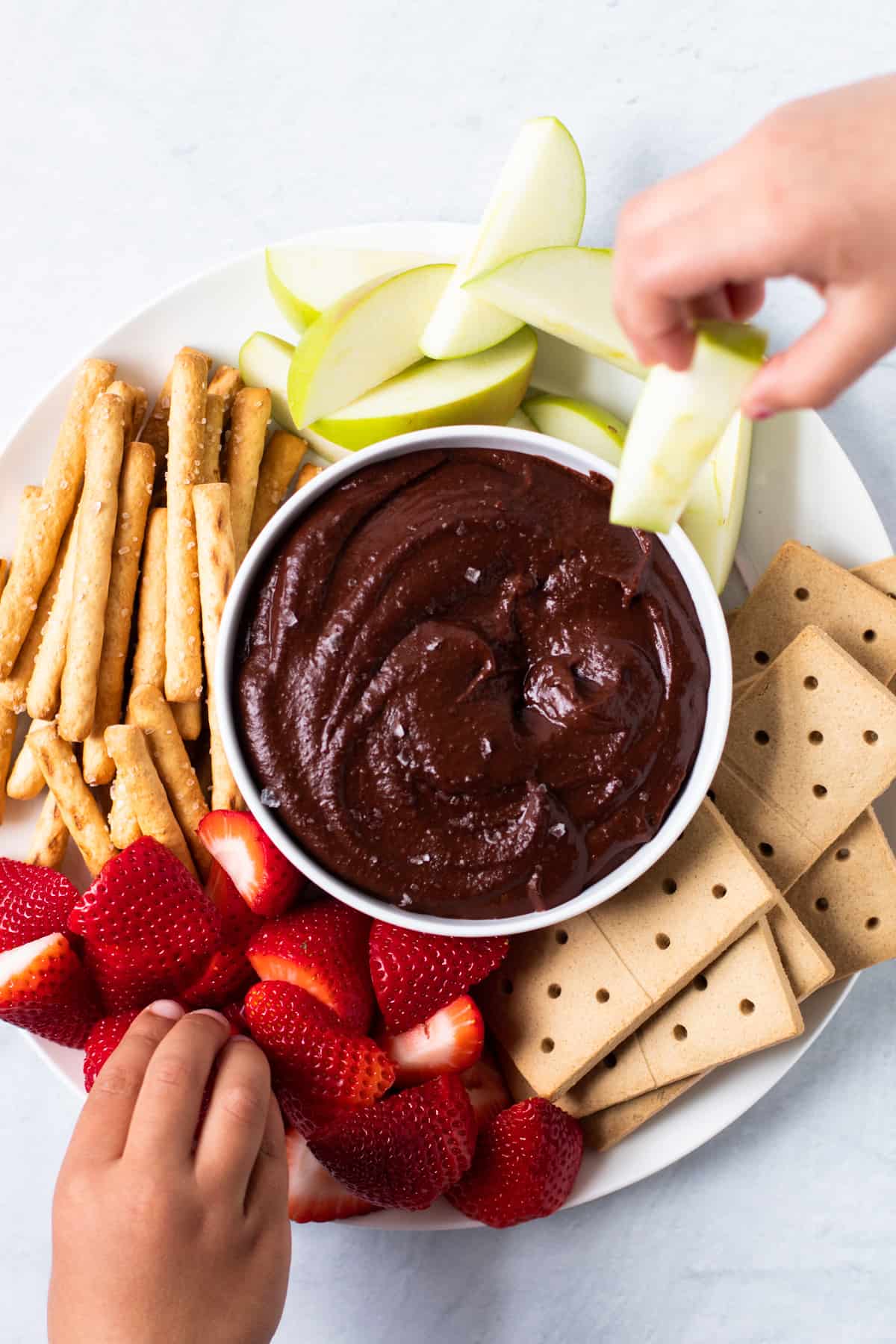 Little hands showing what to eat with chocolate hummus.