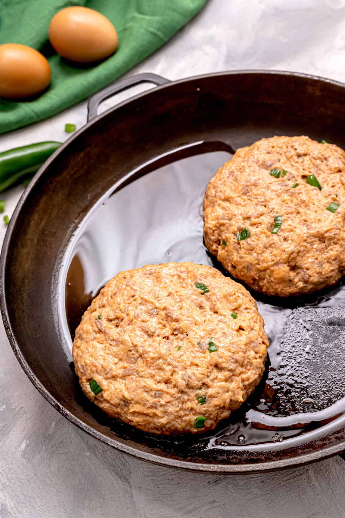 Healthy salmon burgers cooking in a pan.