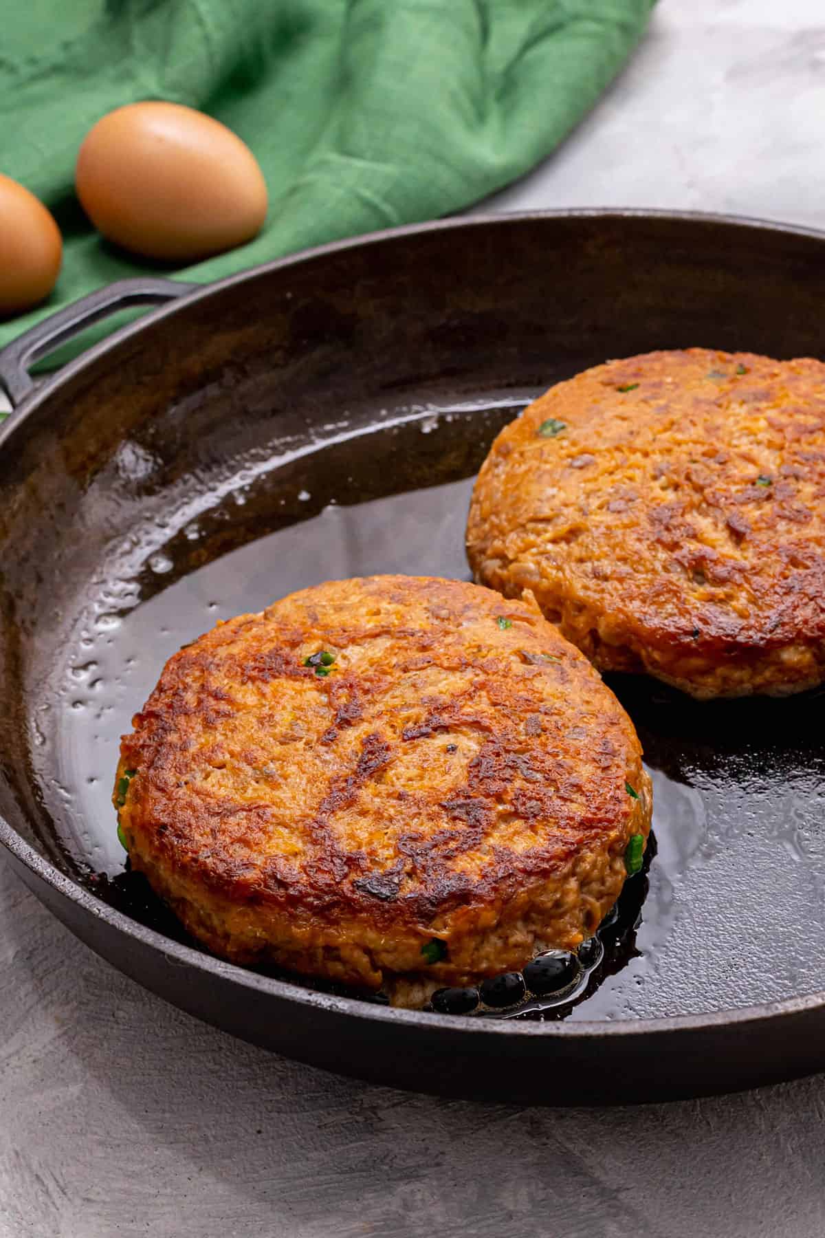 Salmon burgers being cooked in a pan.