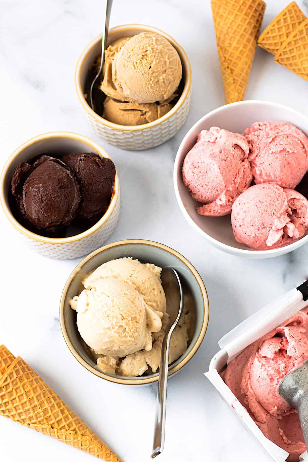 Bowls of peanut butter, chocolate, vanilla, and strawberry nice cream. 