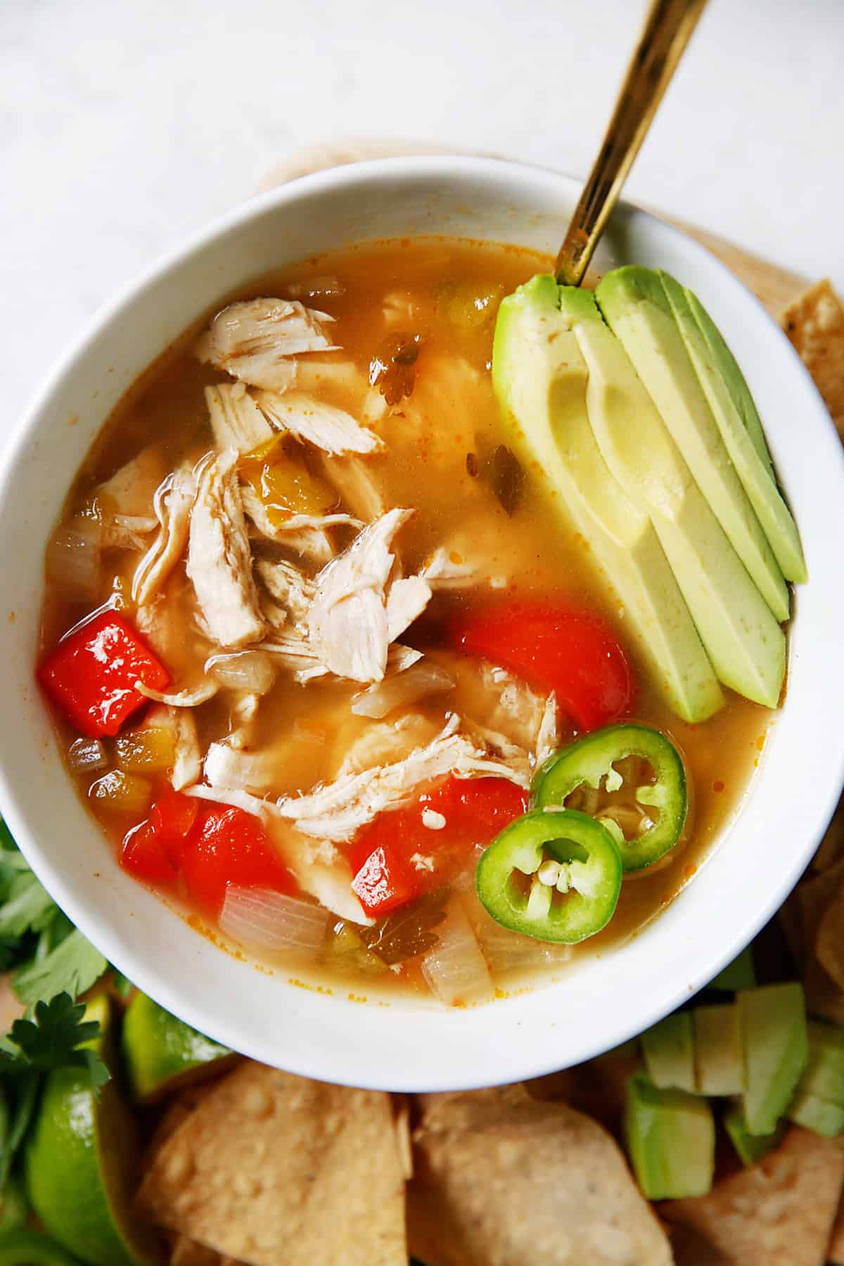A bowl of white chicken chili with avocado.