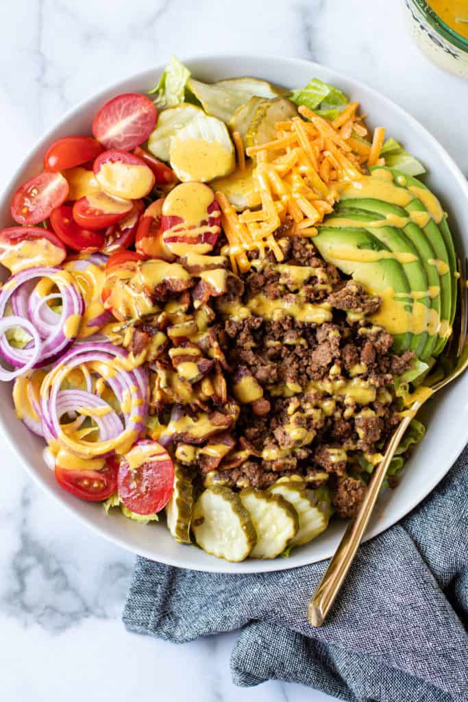 Cheeseburger salad in a bowl with mustard dressing.