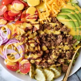 Cheeseburger salad with mustard dressing in a bowl.