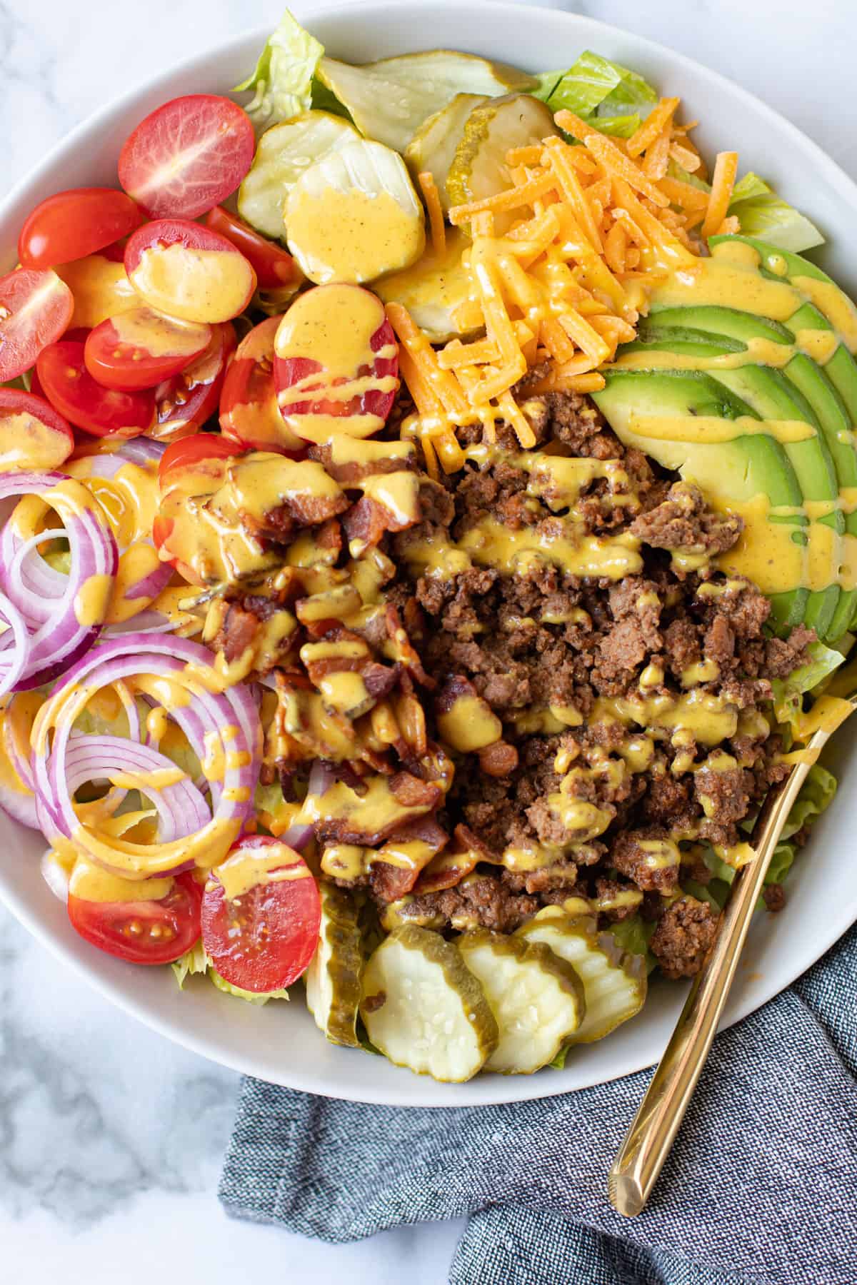 Cheeseburger salad in a bowl with mustard dressing.