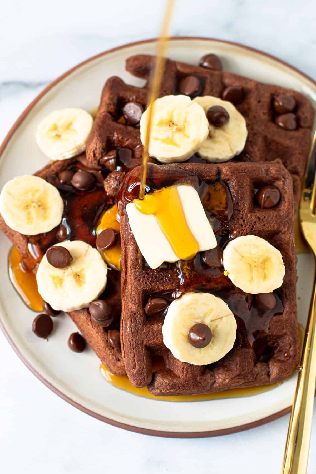 Chocolate banana waffles with chocolate chips, butter and maple syrup.