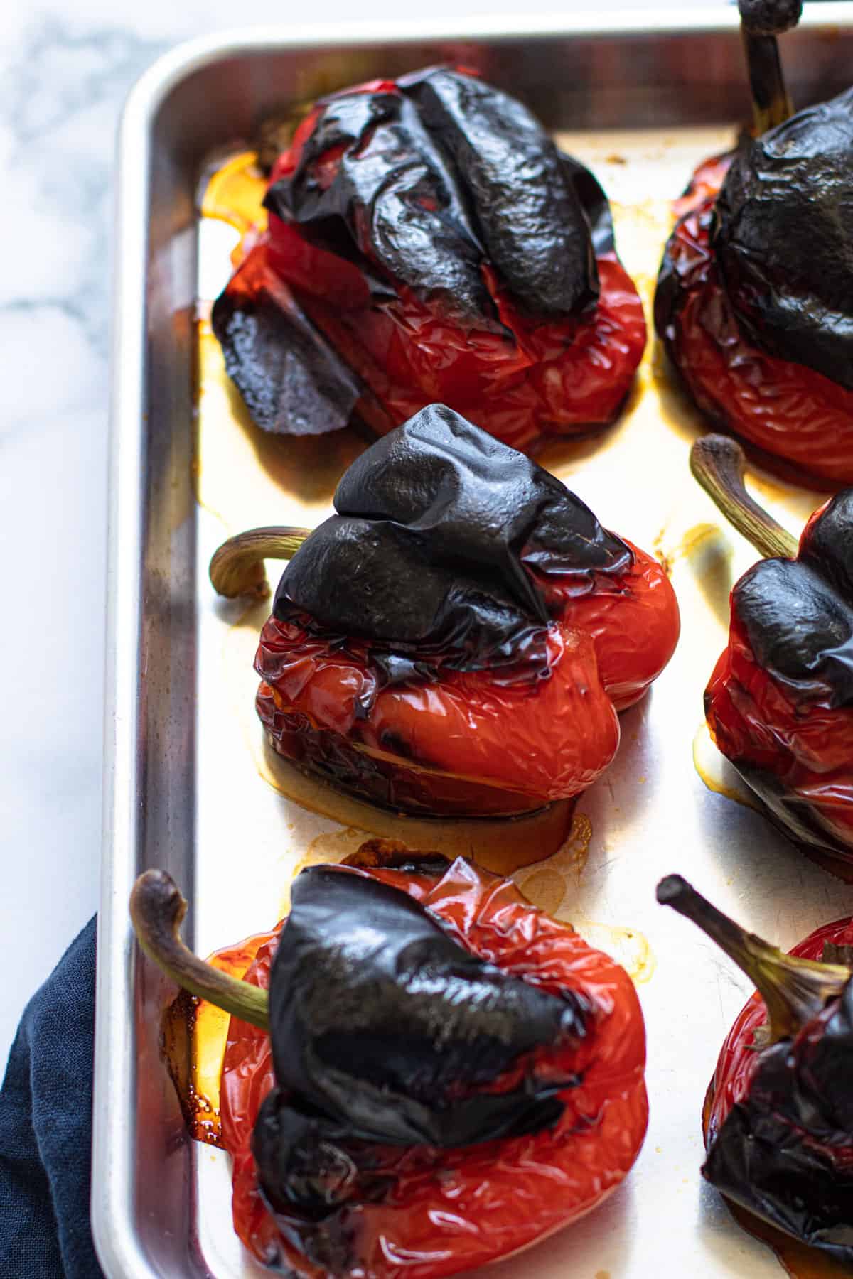 charred bell peppers lined on a baking sheet.