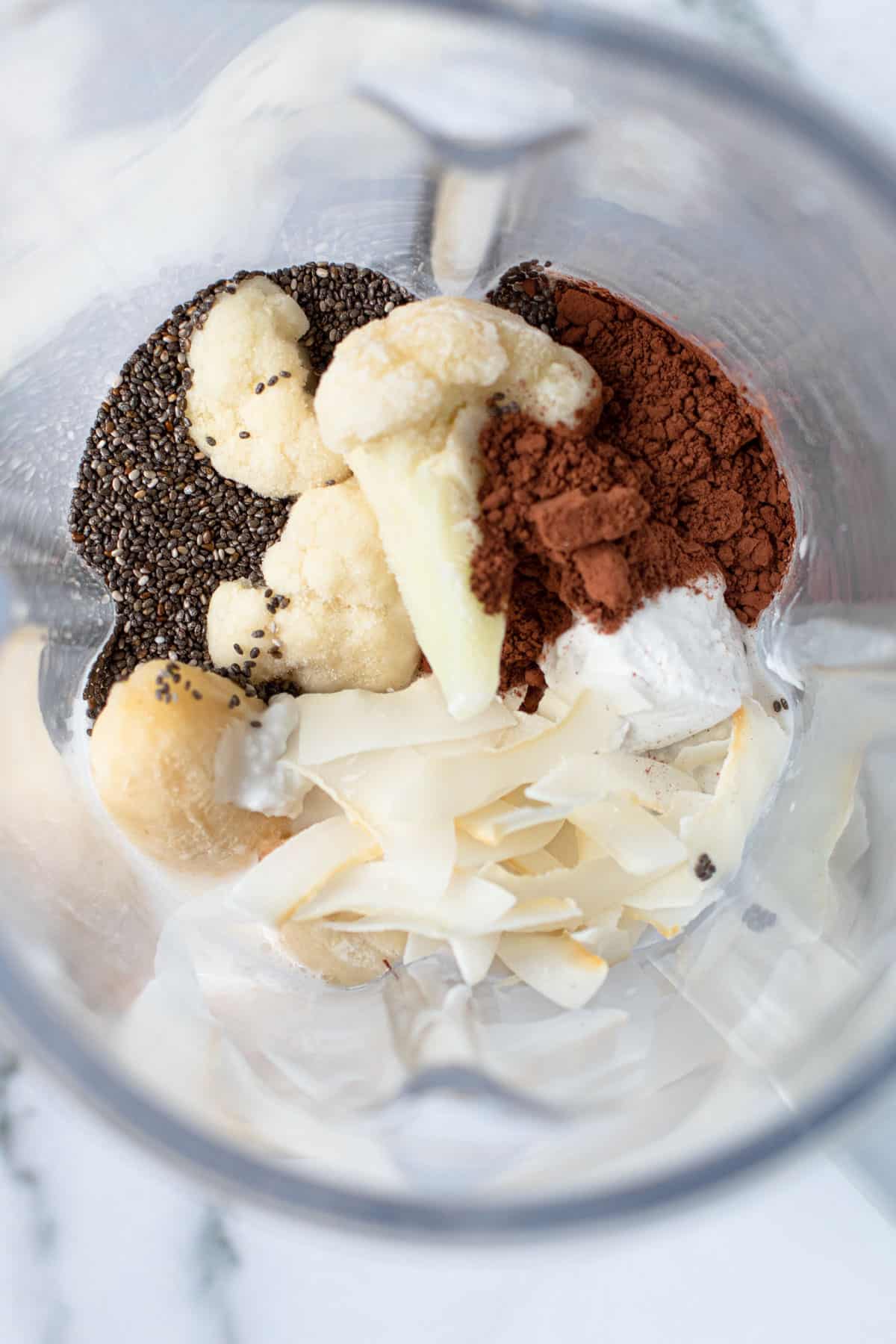 Ingredients for chocolate coconut smoothie including cocoa, banana, coconut and chocolate.
