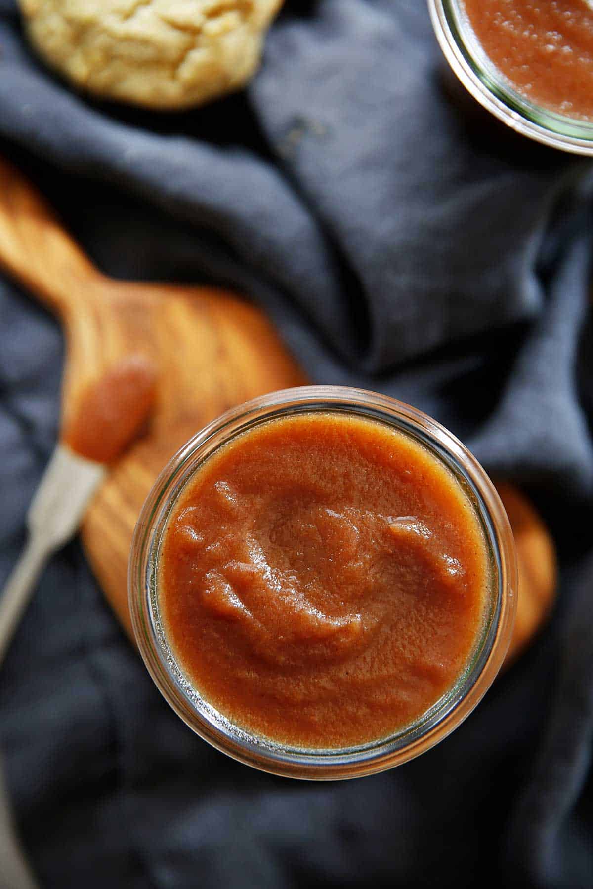 A jar of apple butter on a wooden board.