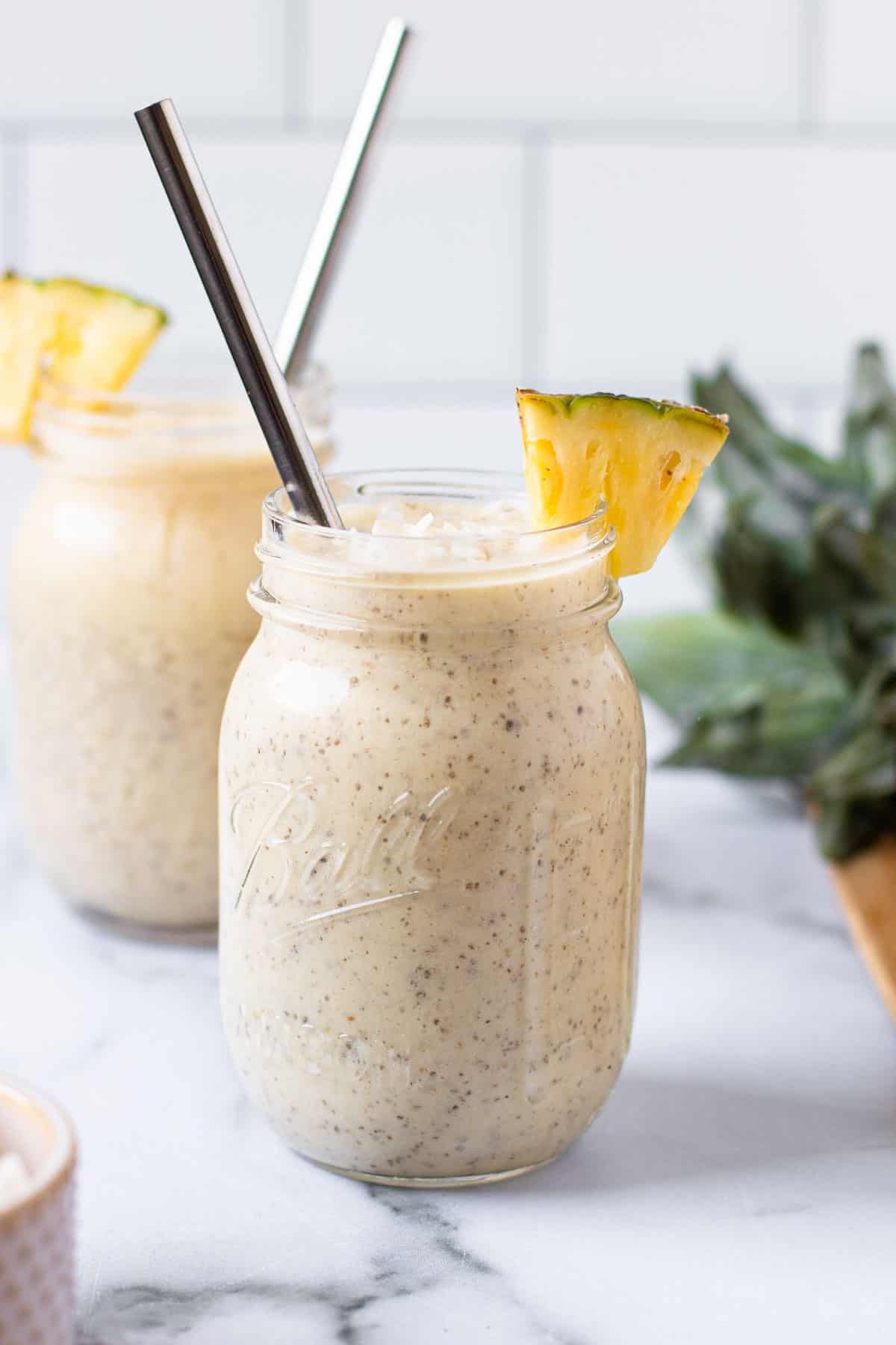 Pina Colada Smoothie with a straw and a pineapple garnish.