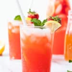 Strawberry lemonade in a glass with ice and a straw.