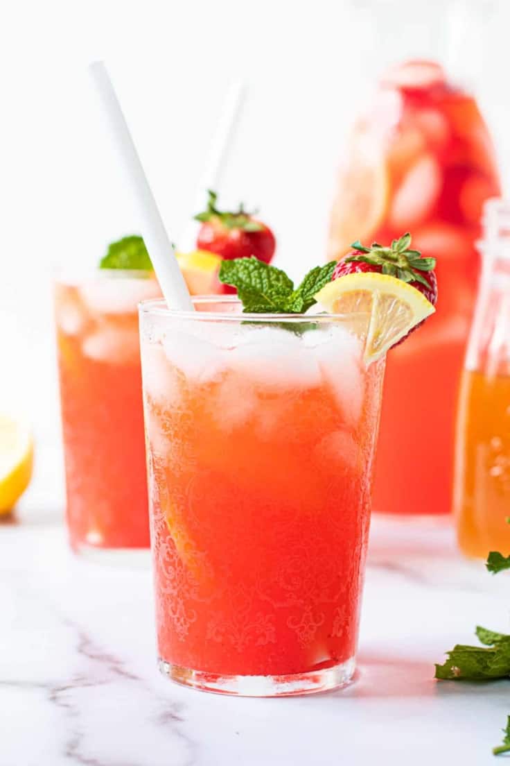Strawberry lemonade in a glass with ice and a straw.