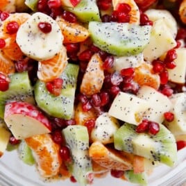 closeup image of a winter fruit salad tossed in yogurt dressing in a bowl.