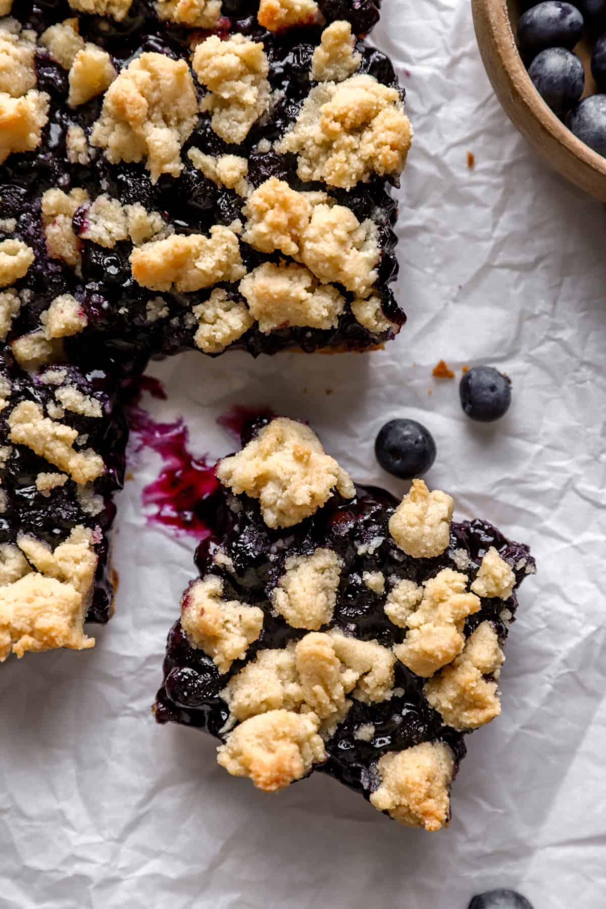 A slab of blueberry crumb bars with one cut. 