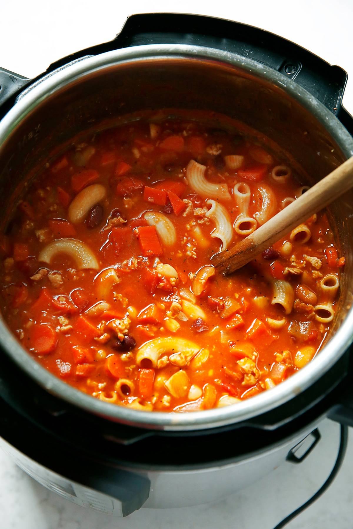 Instant Pot Pasta e Fagioli with a wooden spoon in it.