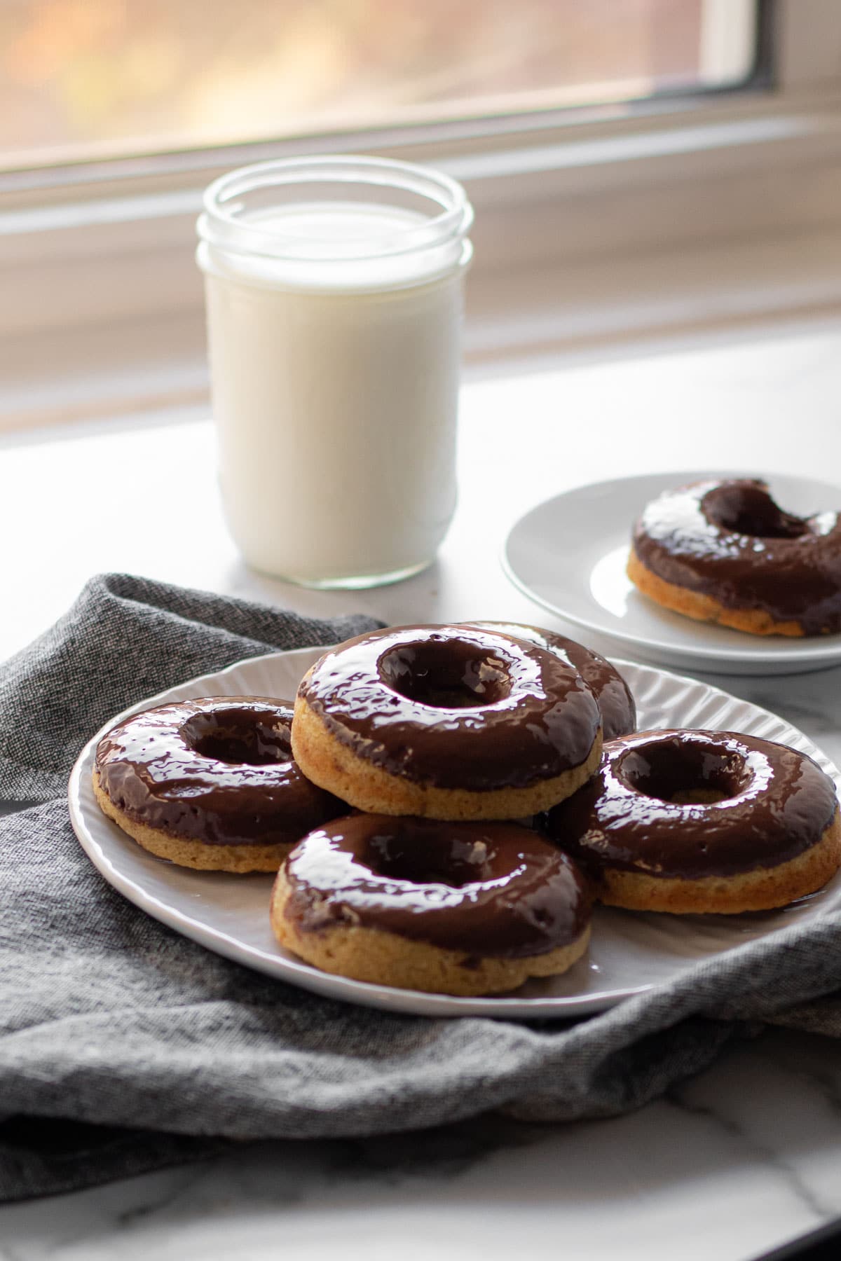 A plate of healthy banana doughnuts near a window with colorful trees.