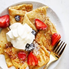 Gluten-Free Crepes with berries, powdered sugar and whipped cream.