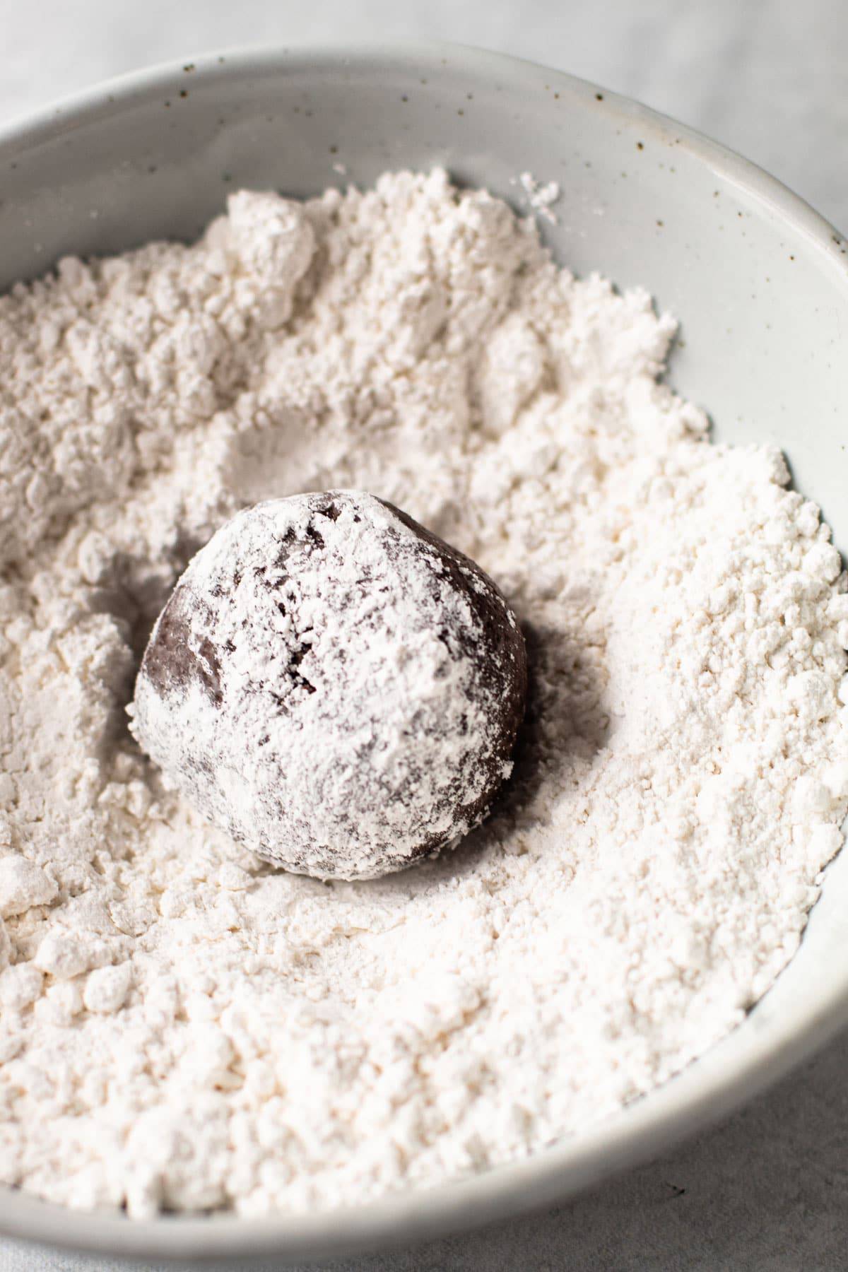 Chocolate cookie dough being coated in powdered sugar.