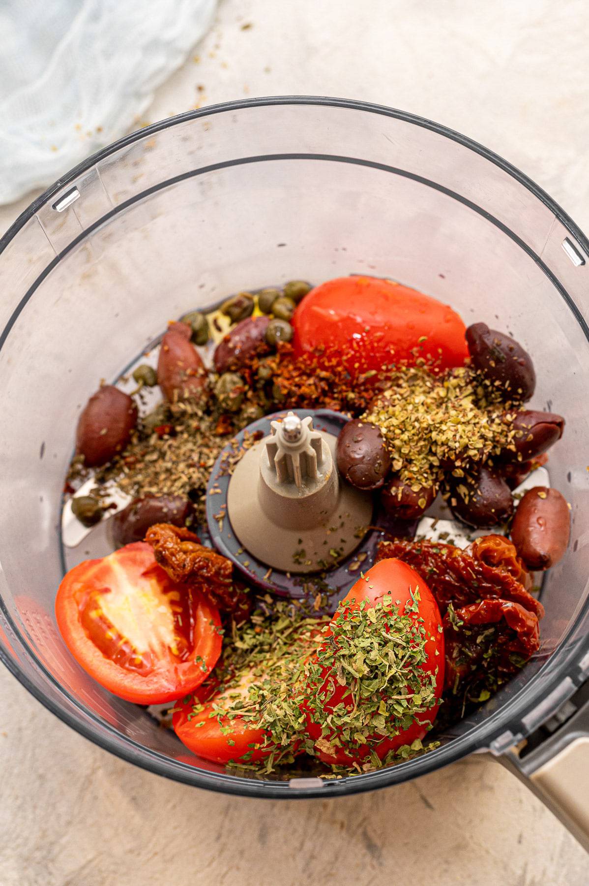 Salmon puttanesca sauce ingredients in a food processor.