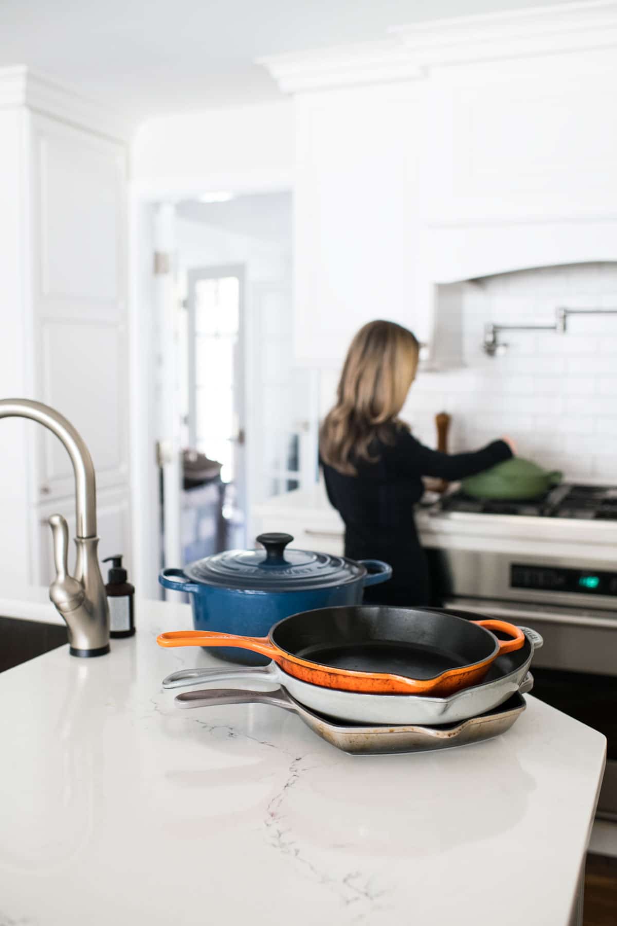 Pans in kitchen with woman cooking in background