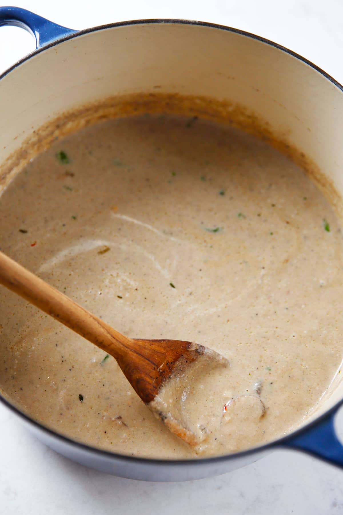 Stirring healthier Cream of Mushroom Soup with a wooden spoon