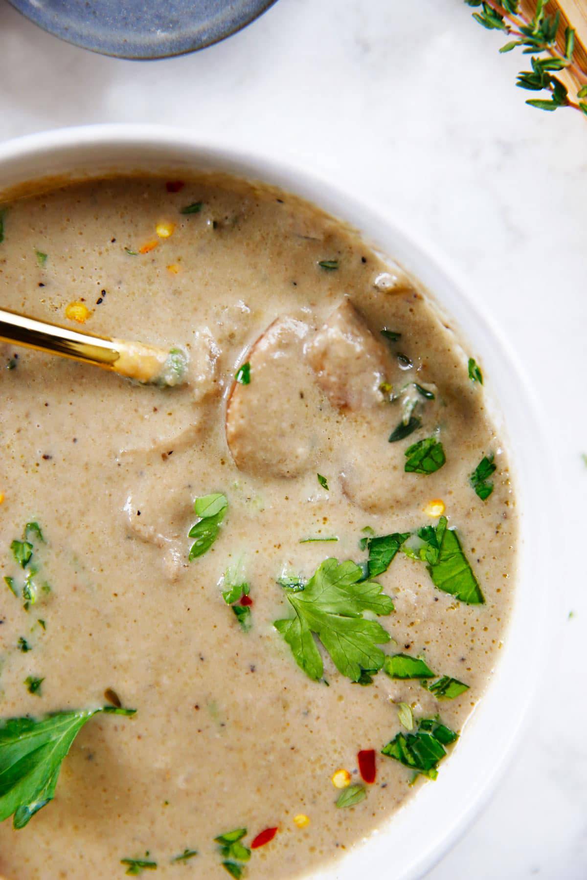 Bowl of Cream of Mushroom Soup topped with fresh parsley with a spoon in the bowl