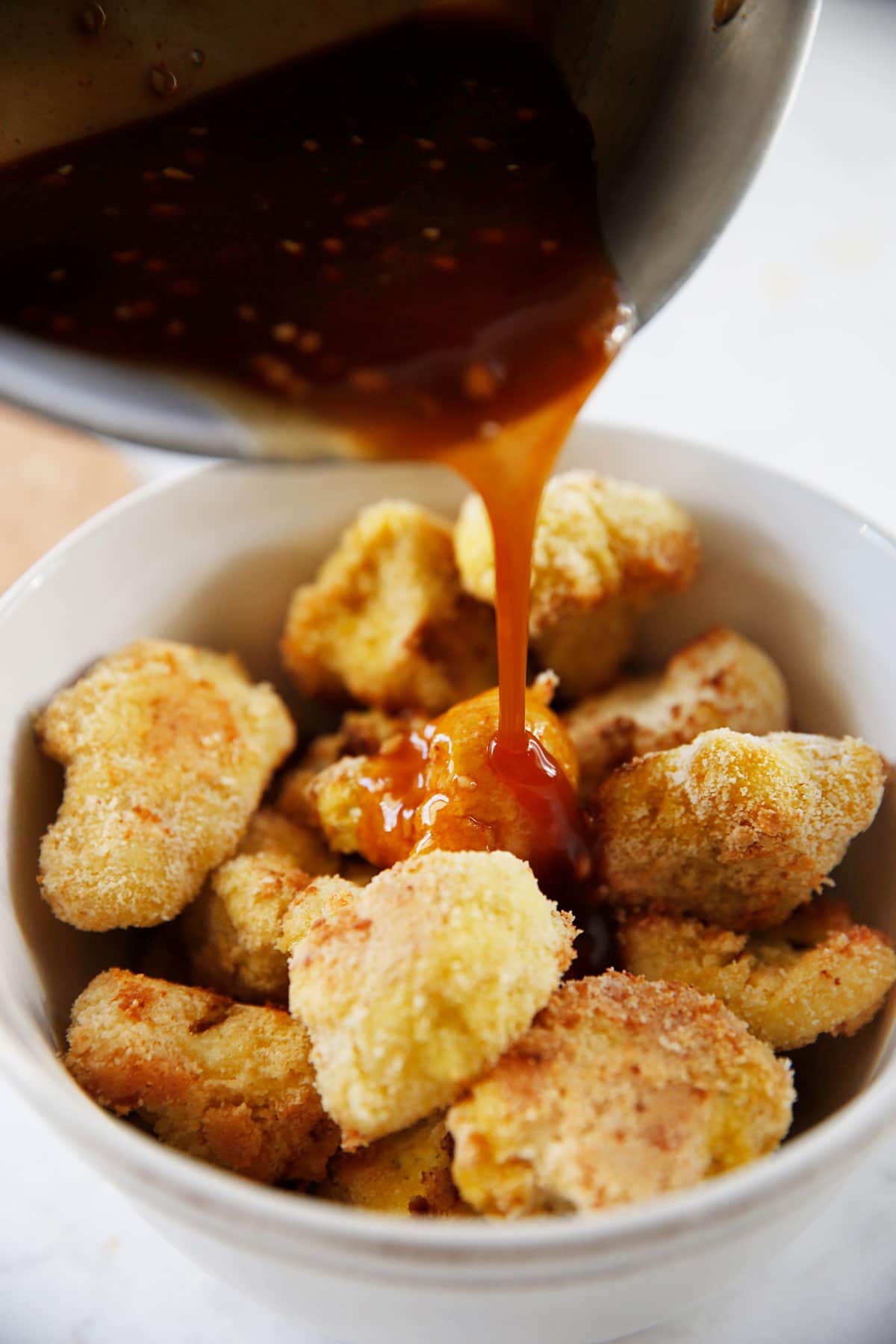 Sauce being poured over cauliflower wings.
