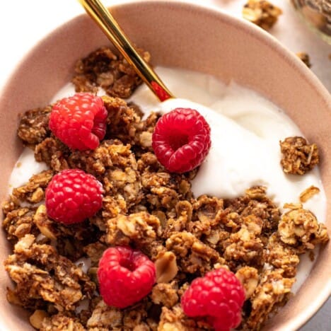 A bowl of peanut butter and jelly granola with fresh raspberries.