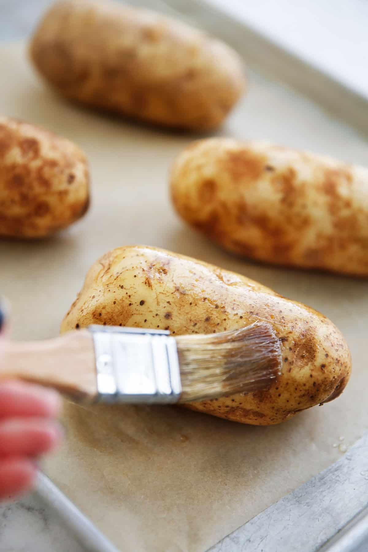Brushing on oil on a russet potato.