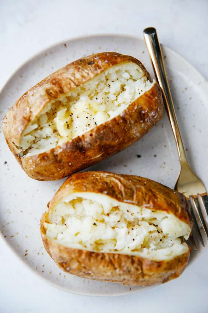 Two baked potatoes on a plate.