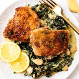 A plate with crispy chicken thighs and lemon greens.