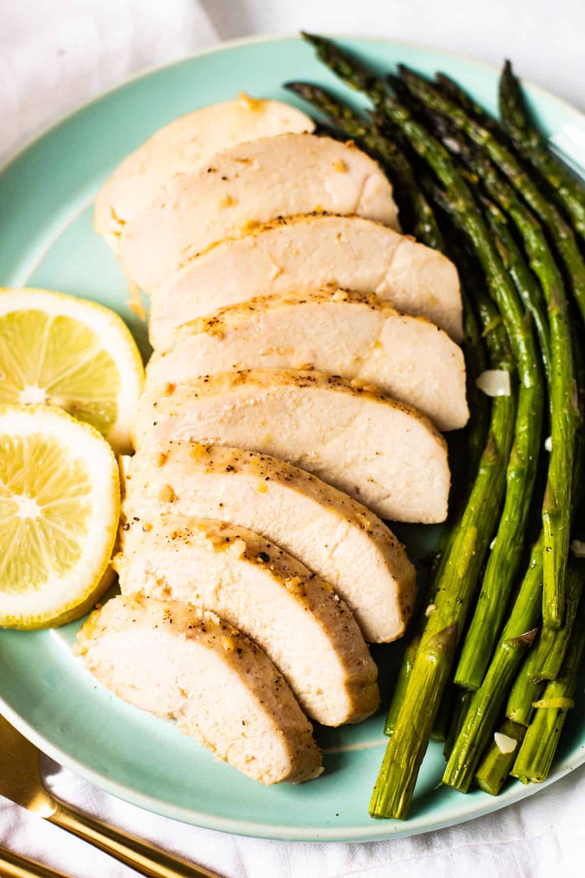 Lemon pepper baked chicken on a plate with asparagus.