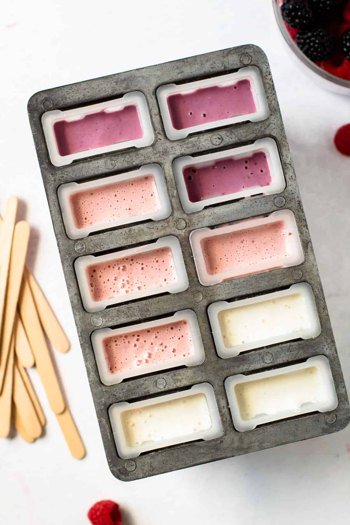 Different fruit yogurt popsicles in molds.