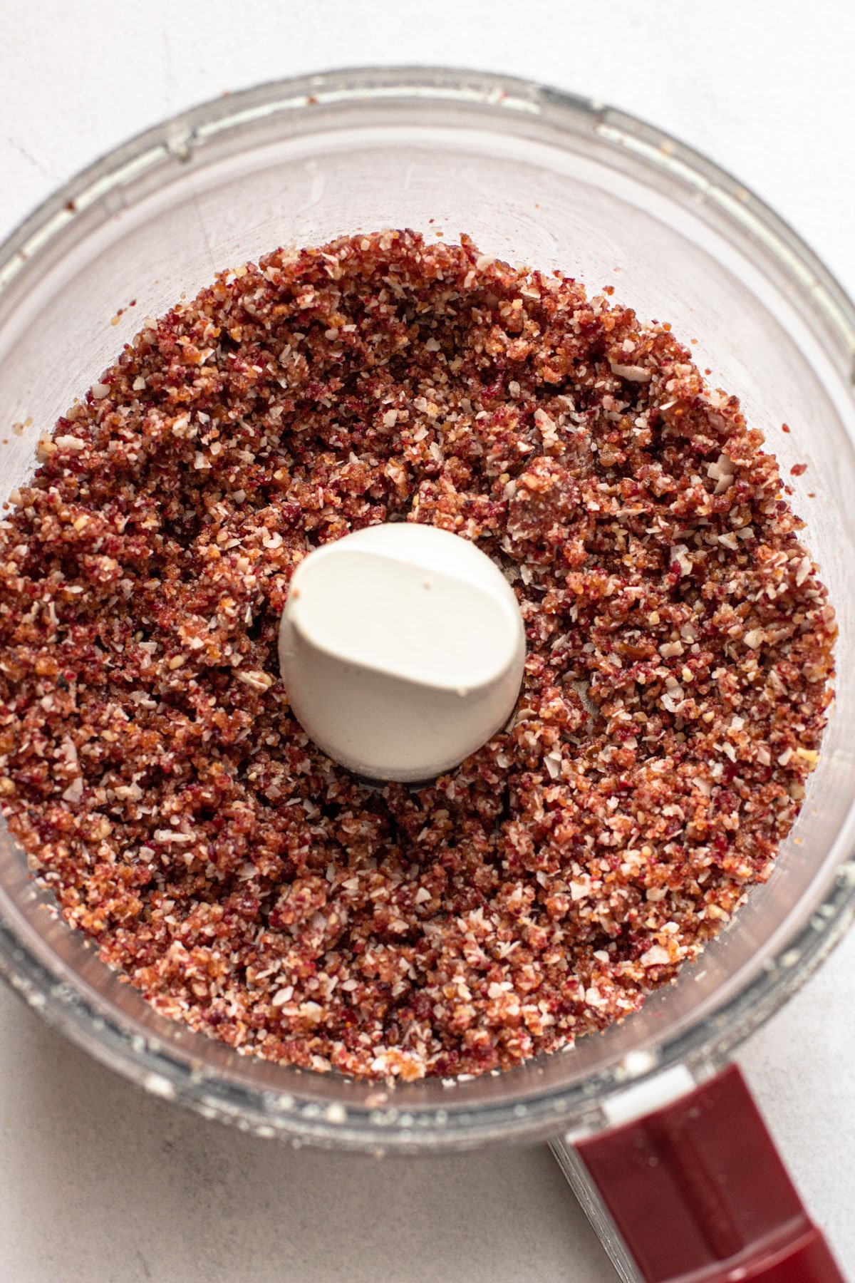 A processed mixture of cranberries and walnuts in a food processor.