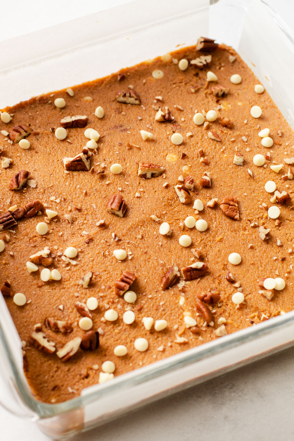 The unbaked batter of pumpkin spice blondies in a glass dish.