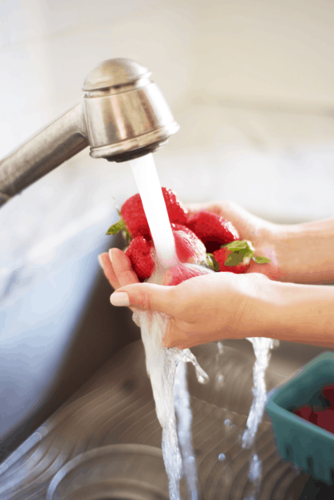 Tap water cleaning strawberries from a sink