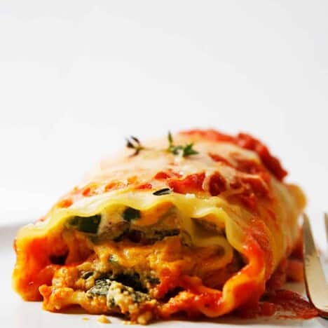 a pumpkin lasagna roll up on a plate, garnished with fresh thyme.