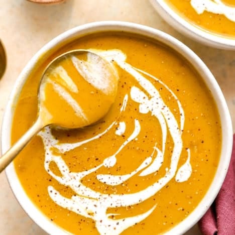 Creamy curry butternut squash soup in a bowl, swirled with coconut milk.