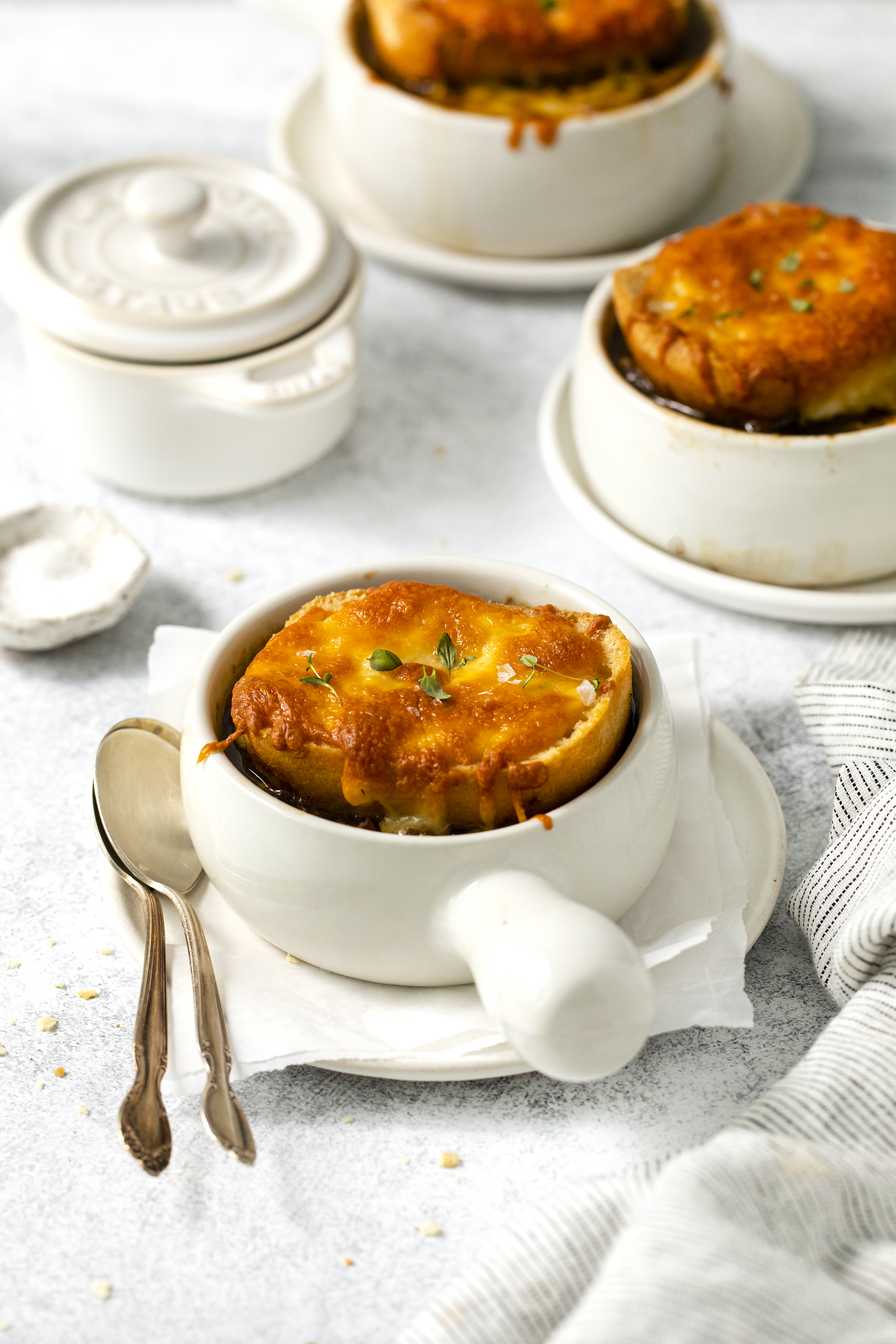 side view of two bowls of french onion soup with one in the forefront.