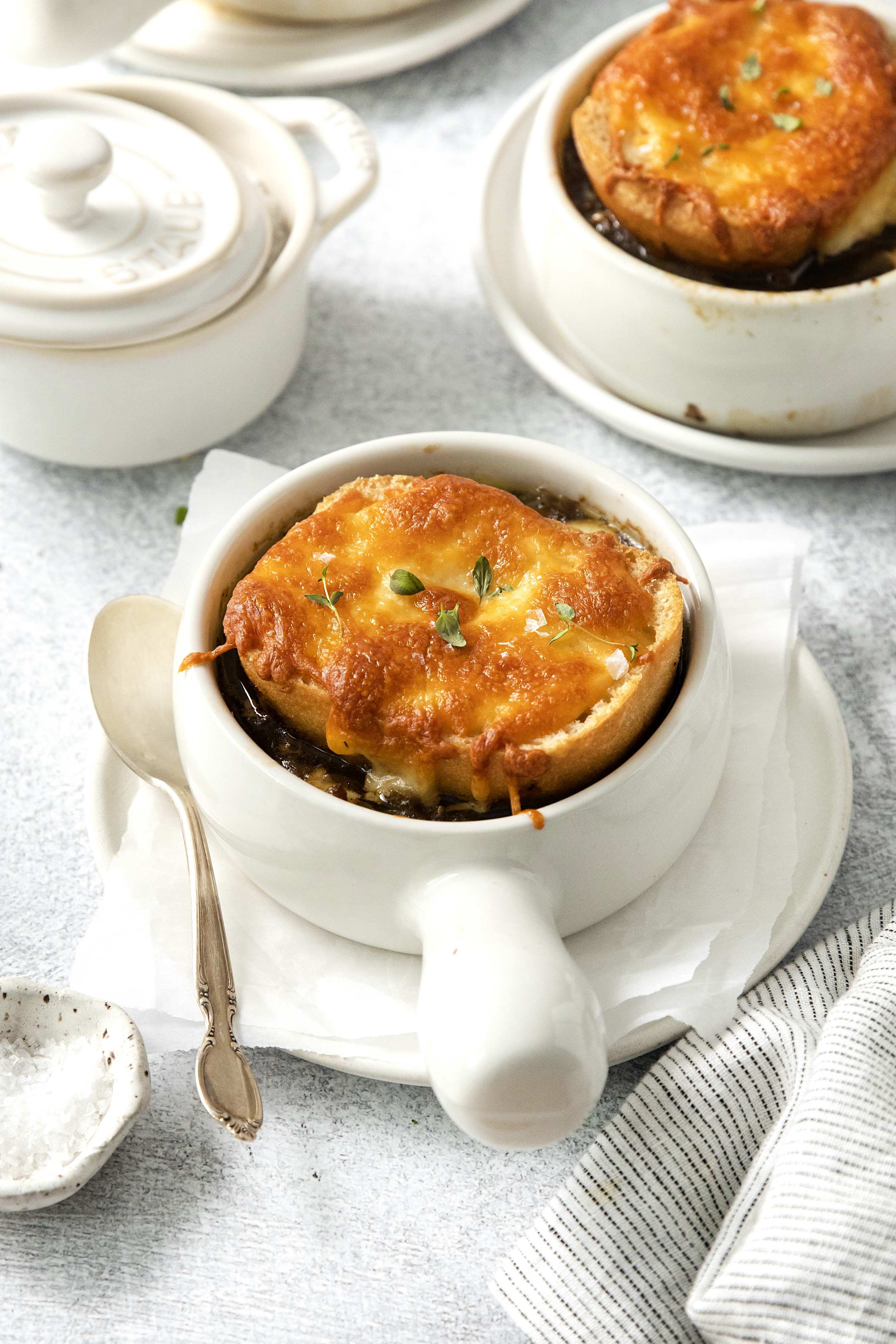 side view of two bowls of cheesy french onion soup.