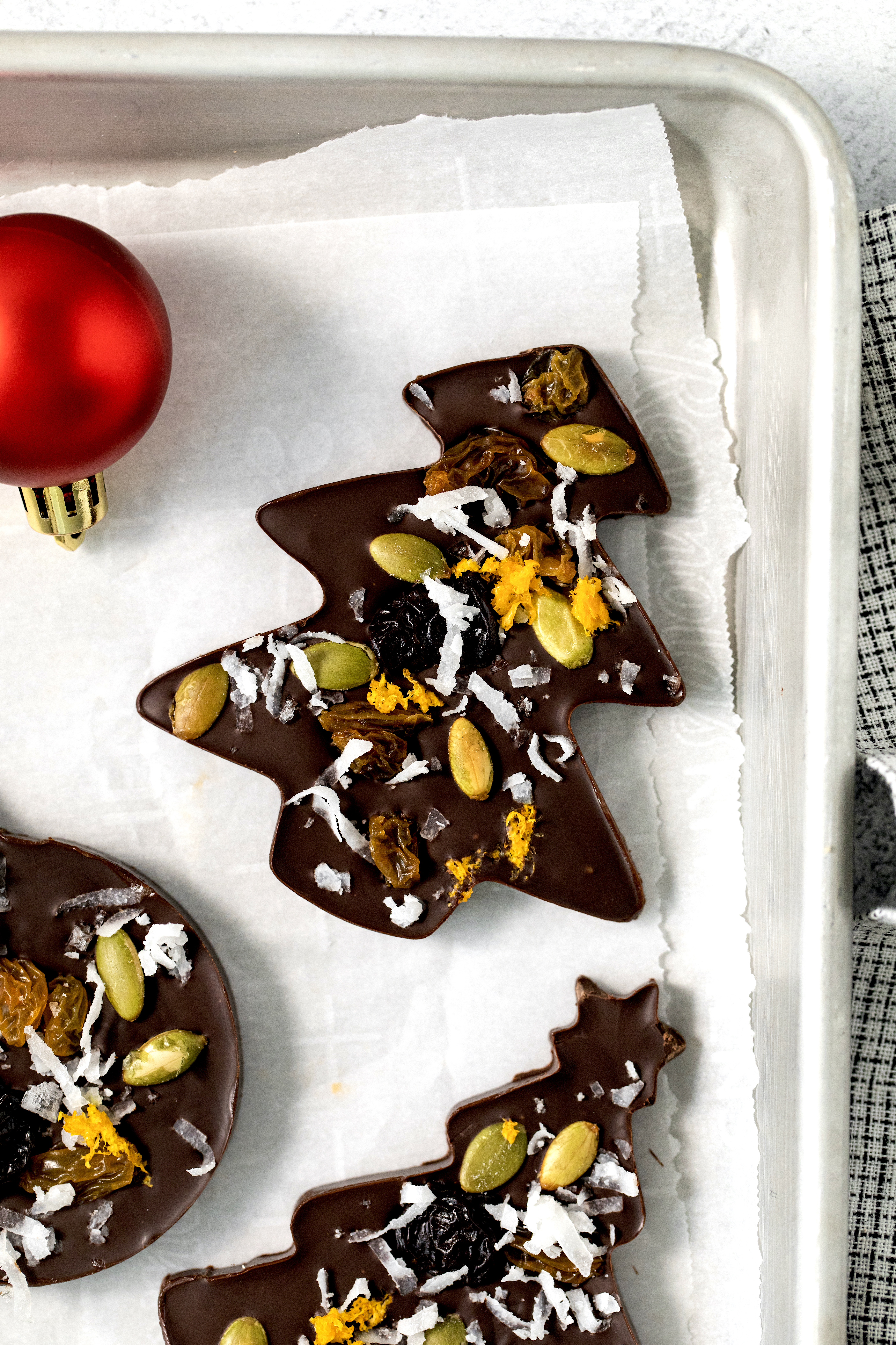 closeup of three pieces of chocolate bark on a piece of parchment paper.