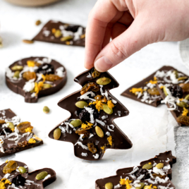 a piece of chocolate bark being lifted off of the counter lined with more bark.