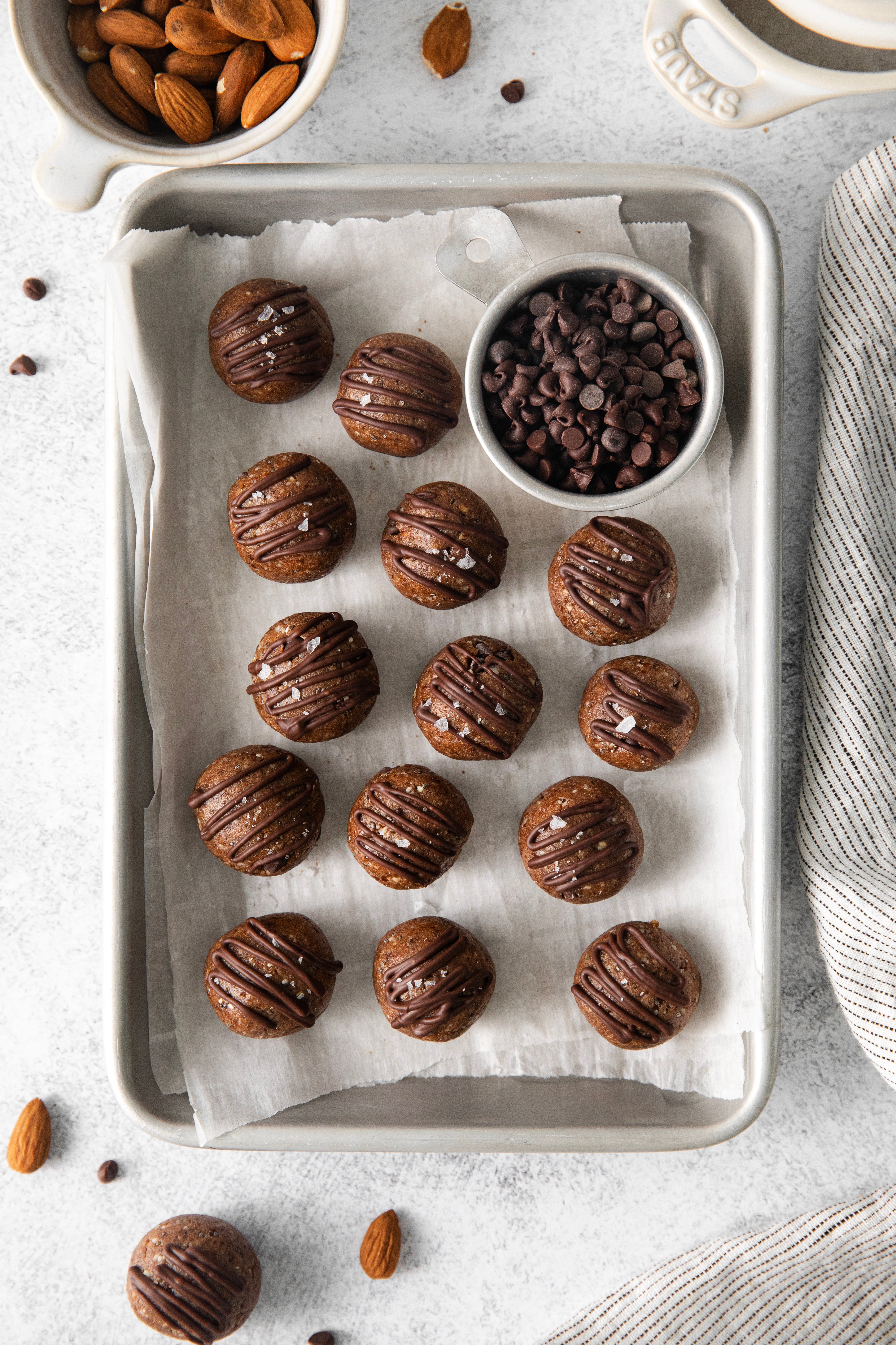 energy balls on a baking sheet being drizzled with melted chocolate.