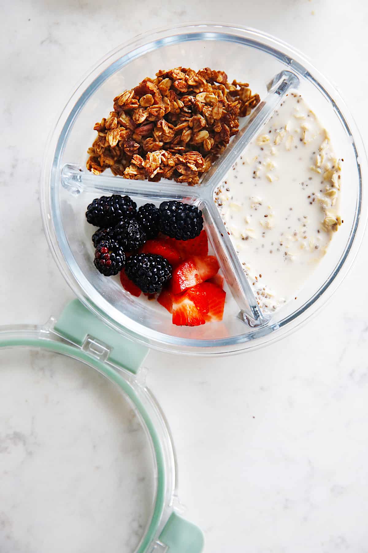a container filled with oats, granola, and fresh berries.