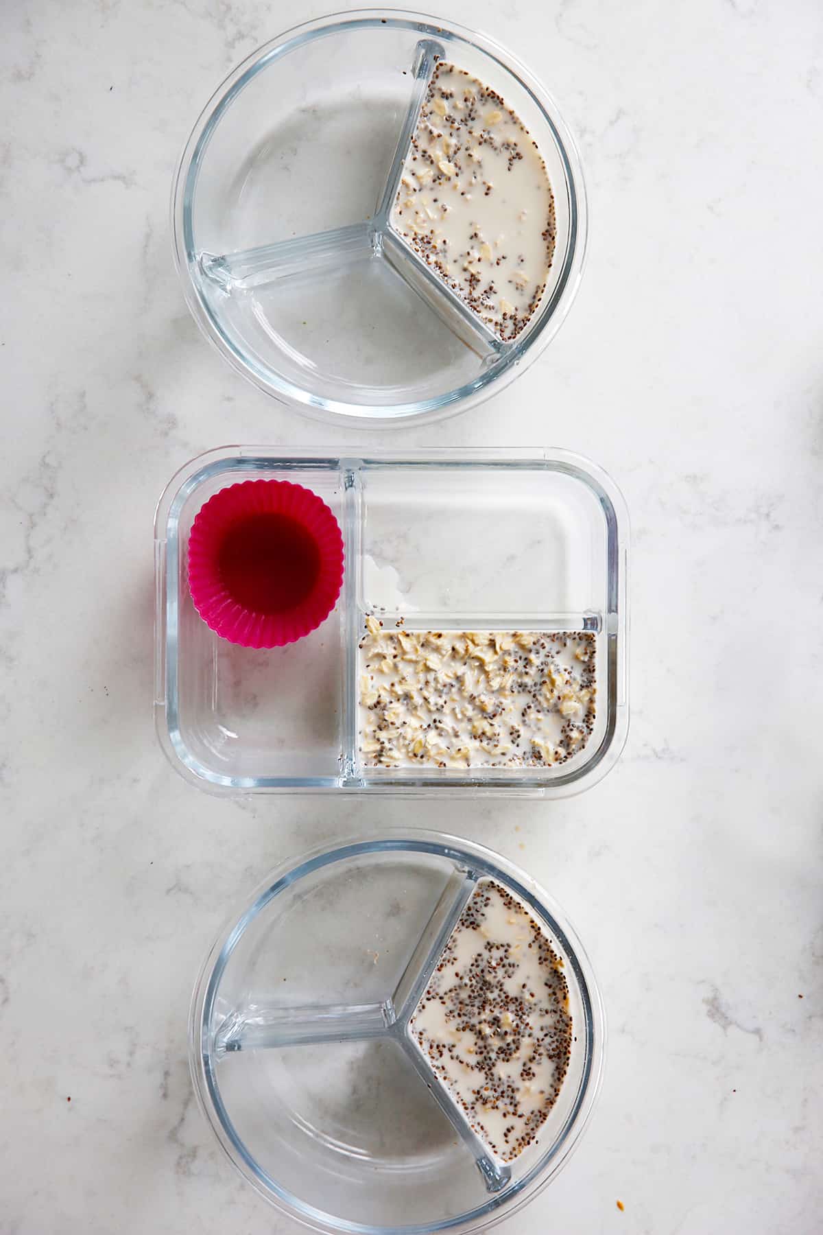 three meal prep containers with oats and chia seeds in milk.