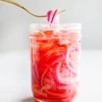 Remove the pickled red onions from the glass jar with a fork.