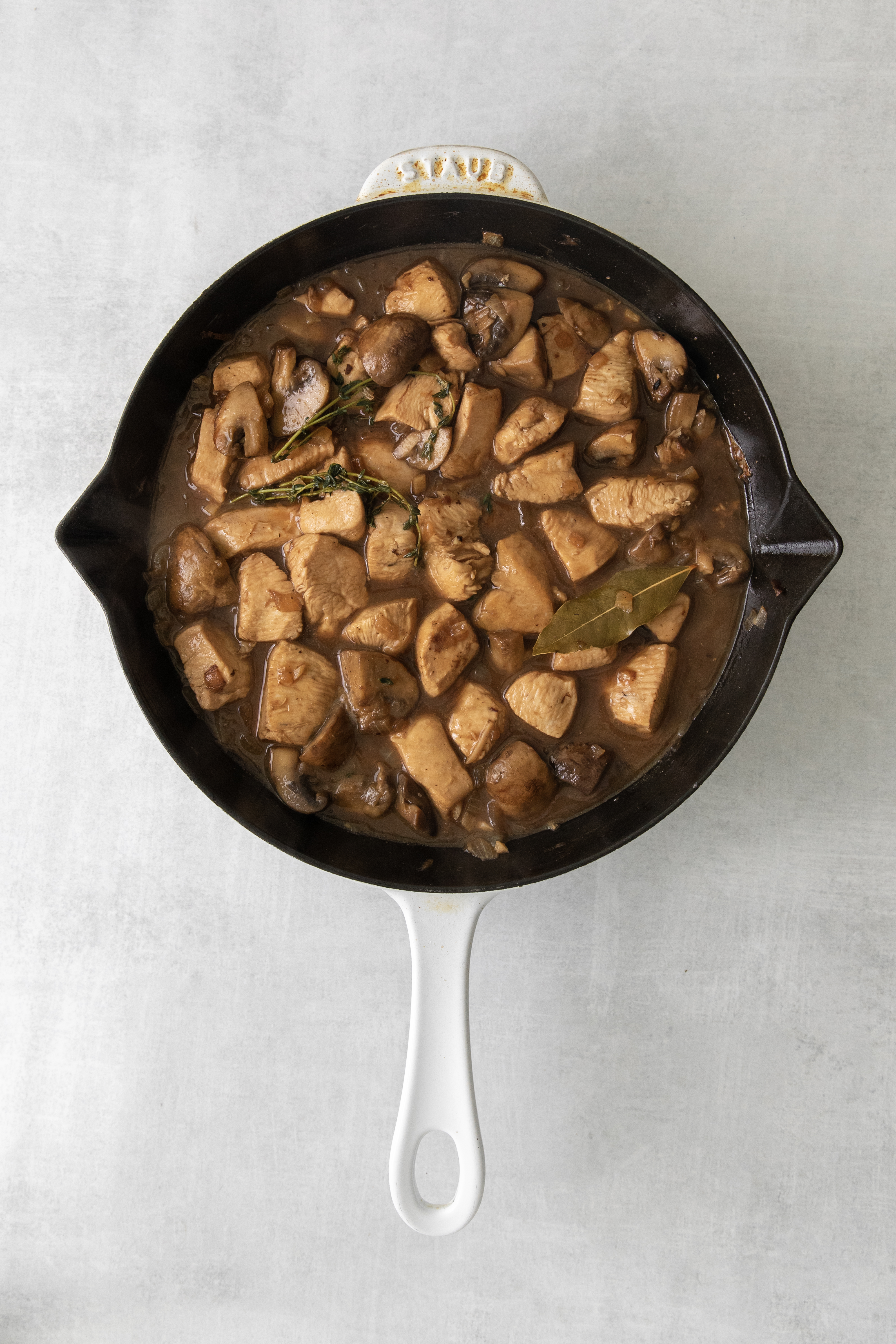 overhead of a skillet filled with chicken and mushroom sauce.