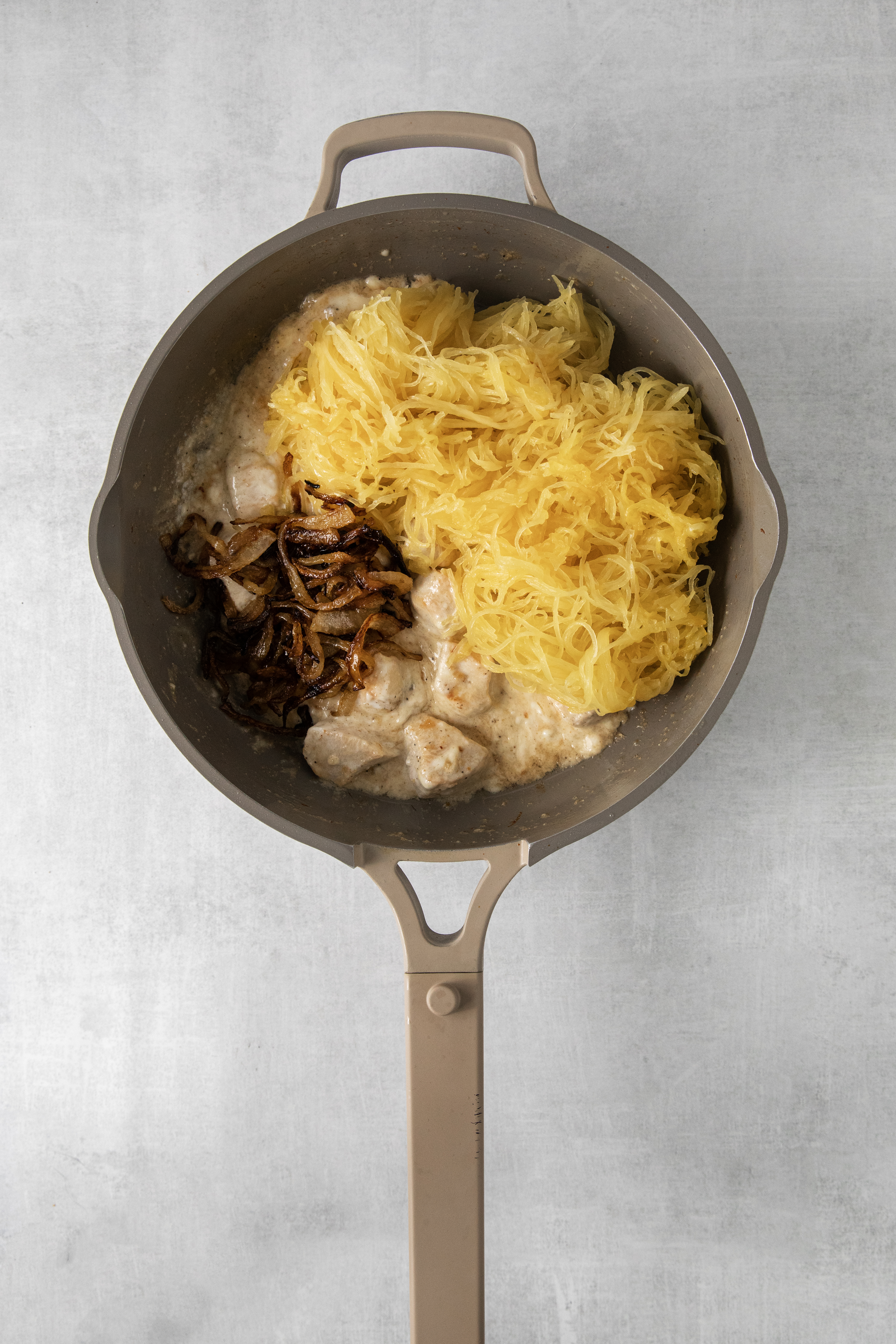 spaghetti squash, chicken, and onions in a pan.
