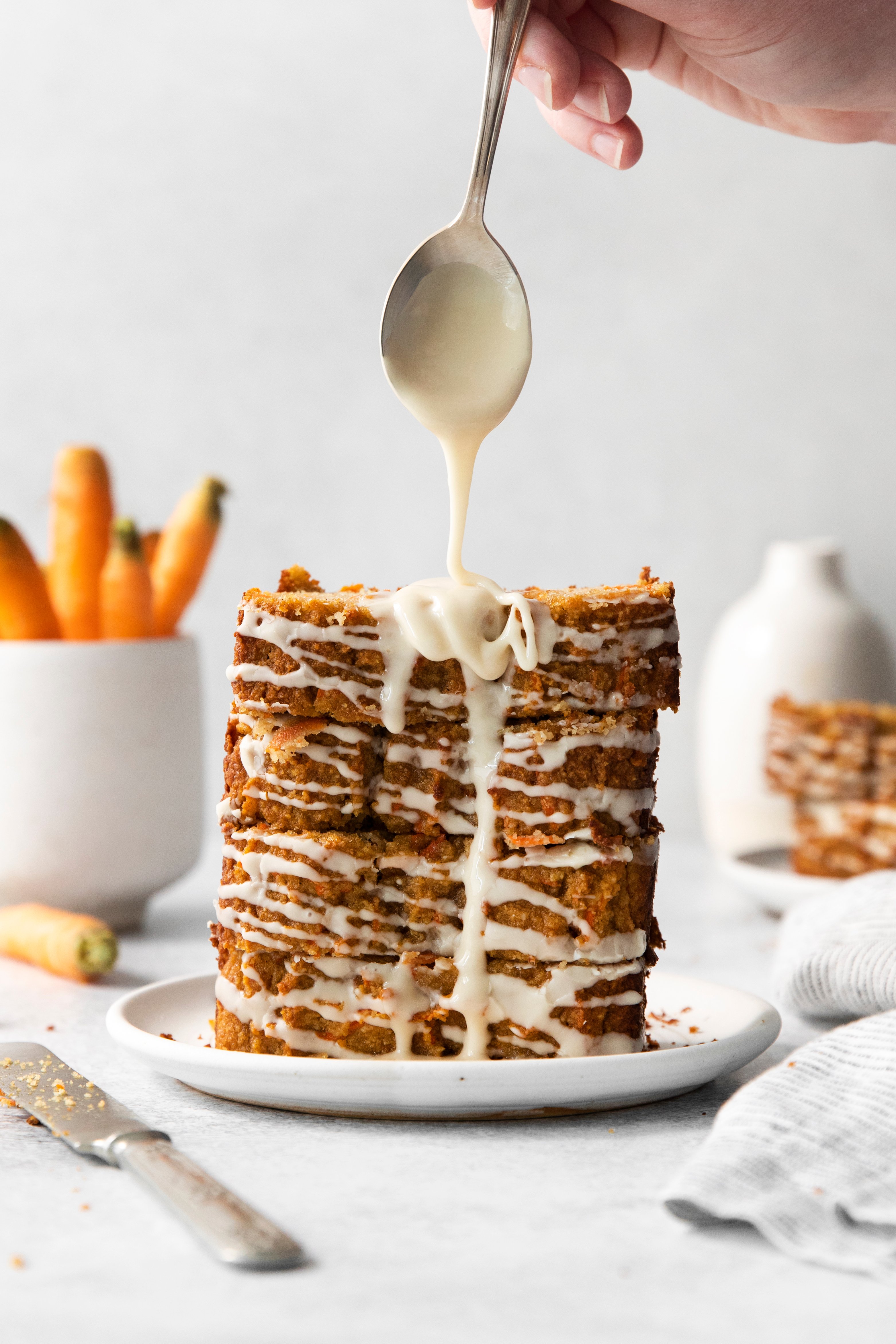 maple glaze being drizzled over a stack of carrot loaf slices.